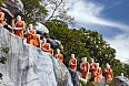 Statues of Buddhist Monks queuing to take lotus flower offerings to Buddha